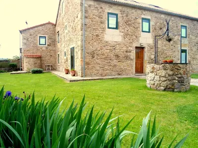 a stone house with a green lawn in front of it at Torres de Moreda in A Estrada