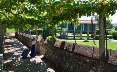 a woman standing next to a wall with her luggage at Torres de Moreda in A Estrada