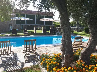 a pool with three chairs and a tree and flowers at Torres de Moreda in A Estrada