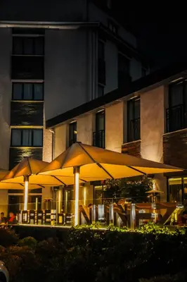 a restaurant with tables and umbrellas in front of a building at Hotel Torre de Núñez in Lugo