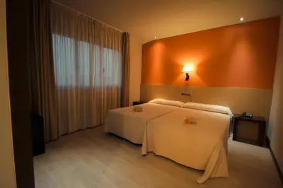 a hotel room with two beds and a window at Hotel Torre de Núñez in Lugo