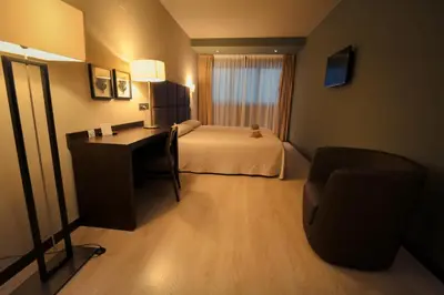 a hotel room with a bed and a desk and a chair at Hotel Torre de Núñez in Lugo