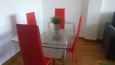 a glass table with red chairs and a plant on it at Precioso apartamento in Lugo