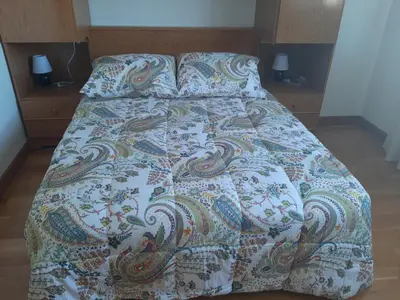 a bed with a comforter and two pillows at Precioso apartamento in Lugo