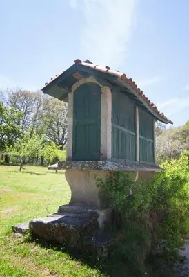 a small building with a green door on a field at Casa Blanco in Palas de Rei