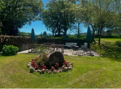 a garden with a flower bed and tables and umbrellas at Casa Blanco in Palas de Rei