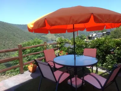 a table and chairs with an umbrella on a deck at Ribera Sacra ( apartamento Rural ) in Ferreira de Panton
