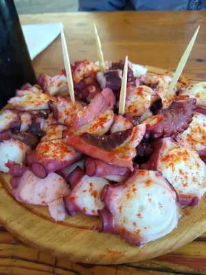 a plate of food with shrimp on a wooden table at Ribera Sacra ( apartamento Rural ) in Ferreira de Panton