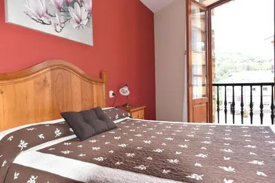 a bedroom with a large bed with red walls at Hotel Restaurante Casa Petronila in Taramundi