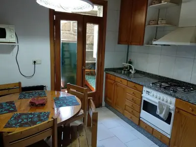 a kitchen with a wooden table and a dining room at O Tipico in Ribadavia