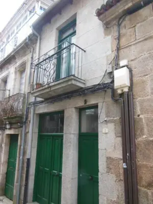 a building with two green doors and a balcony at O Tipico in Ribadavia