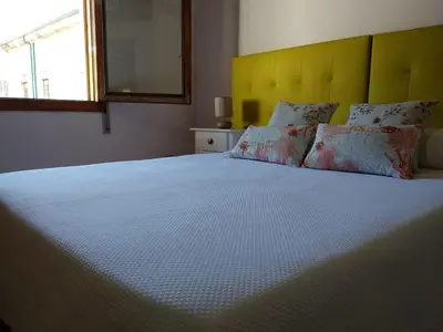 a bedroom with a large white bed with a yellow headboard at O Tipico in Ribadavia