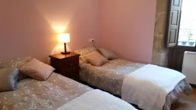 two beds in a room with a lamp on a table at Apartamento con vistas a la catedral in Santiago de Compostela