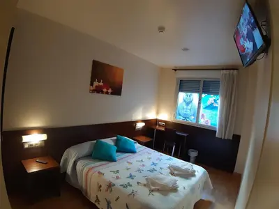 a bedroom with a bed and a tv on the wall at Hostal Nirvana in Ponferrada