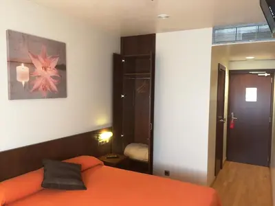 a bedroom with an orange bed and a mirror at Hostal Nirvana in Ponferrada
