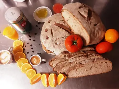 a loaf of bread with a tomato on top and oranges at Hostal Nirvana in Ponferrada