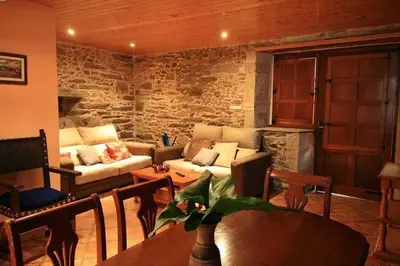 a living room with a couch and a stone wall at Casa Labazá in Villarmayor