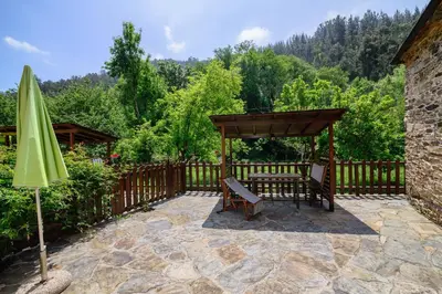 an umbrella and a bench on a patio with a fence at Casas da Lexa in Taramundi