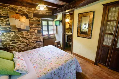 a bedroom with a bed and a stone wall at Casas da Lexa in Taramundi