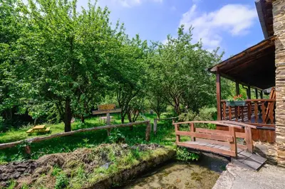 a wooden bench next to a river with trees at Casas da Lexa in Taramundi