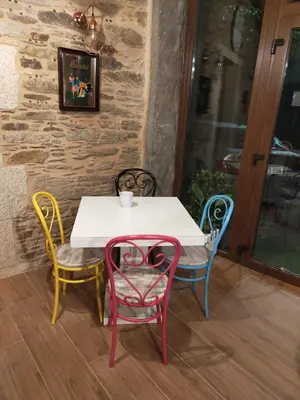 a table with four chairs and a white table with a cup on it at Casa do Horreo in O Pino
