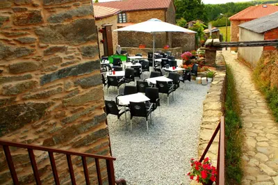 a group of tables and chairs in front of a building at Casa do Horreo in O Pino