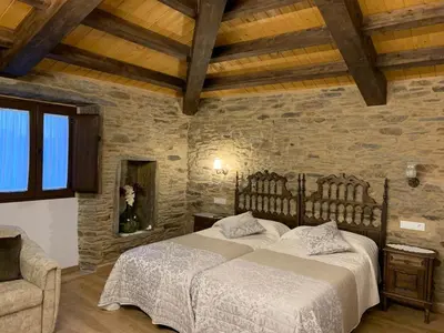 a bedroom with a bed and a stone wall at Casa do Horreo in O Pino
