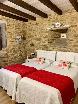 two beds in a room with a stone wall at Casa do Horreo in O Pino
