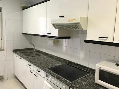 a white kitchen with a sink and a microwave at vivienda vacacional Iguazu in Ribadeo