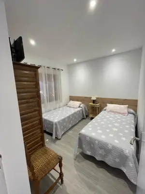 a room with two beds and a chair in it at Chalet xeitosiño in Astorga