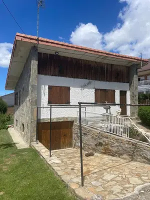 a house with wooden doors and a fence in front of it at Chalet xeitosiño in Astorga