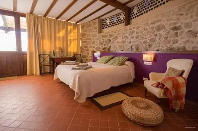 a bedroom with a bed and a chair in a room at O Canto da Terra in Pantón