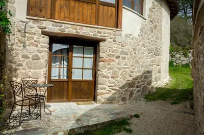 a stone house with a wooden door and a table and chairs at O Canto da Terra in Pantón