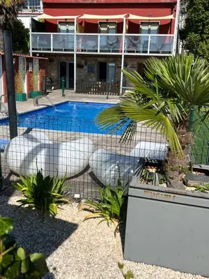 a fence around a swimming pool in front of a building at Casa Costoya in Arzúa