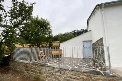 a dog standing behind a gate next to a building at Casa Rural As Bodegas - Villa Rustica Asturias - Boal in Boal