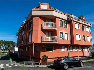 a red building with a car parked in front of it at Apartment Edificio Bahia II by Interhome in Miño