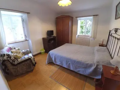 a bedroom with a bed and a chair and two windows at Holiday Home El Olivo by Interhome in Puentedeume