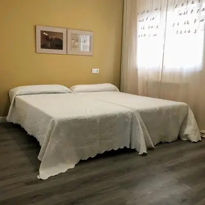 two beds with white covers in a room with a window at La Barranca in Barreiros