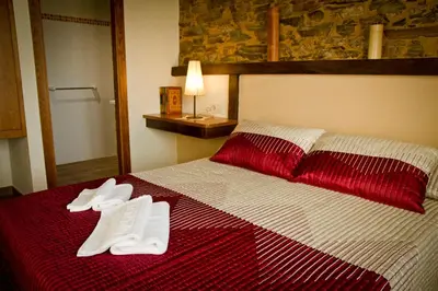 a bedroom with a red and white bed with white slippers at Casa da Lembranza in Fonsagrada