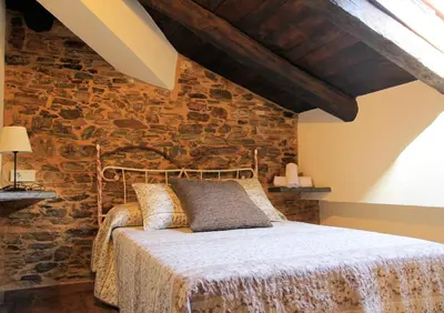 a bedroom with a bed with a stone wall at Casa da Lembranza in Fonsagrada