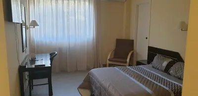 a bedroom with a bed and a desk and a window at Hospedaje O Camiño in O Barco de Valdeorras