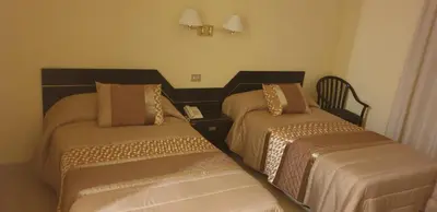 a room with two beds and a chair in it at Hospedaje O Camiño in O Barco de Valdeorras
