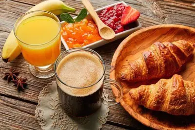 a table with a glass of juice and a plate of croissants at Hospedaje O Camiño in O Barco de Valdeorras