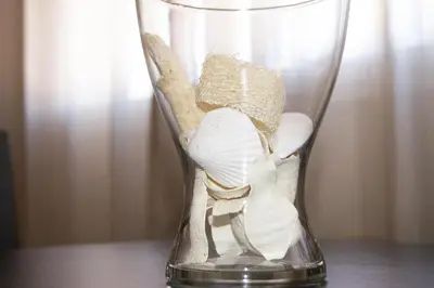 a glass vase filled with shells on a table at Apartamentos Turísticos Guillermo in Palas de Rei