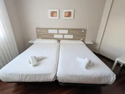 a bedroom with two beds with white sheets at Apartamentos Turísticos Guillermo in Palas de Rei