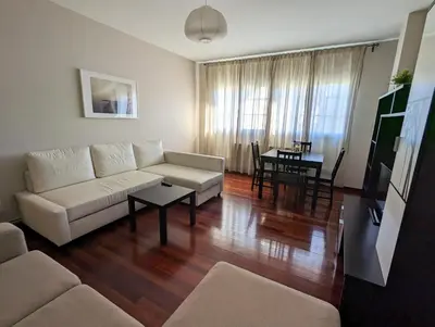 a living room with a white couch and a table at Apartamentos Turísticos Guillermo in Palas de Rei