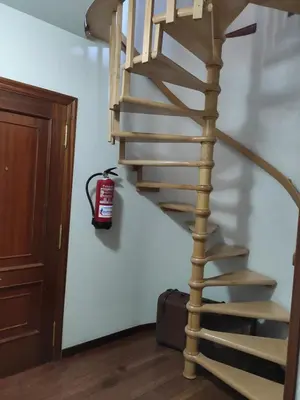 a wooden spiral staircase with a fire extinguisher on the wall at DÚPLEX SANABRIA in El Puente