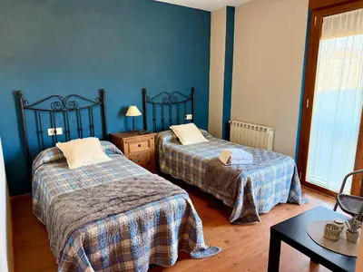 a bedroom with two beds and a table and a chair at Hostal El Horno in Molinaseca