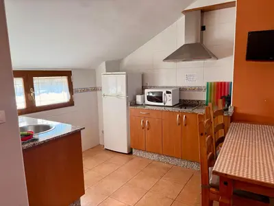 a small bedroom with a bed with an orange wall at Hostal El Horno in Molinaseca