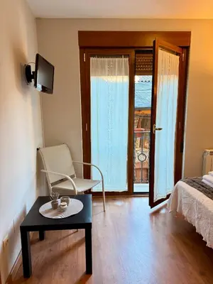a room with a bed and a table and a window at Hostal El Horno in Molinaseca